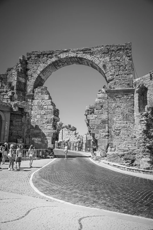 people are standing outside a stone arch in the middle of a dirt field