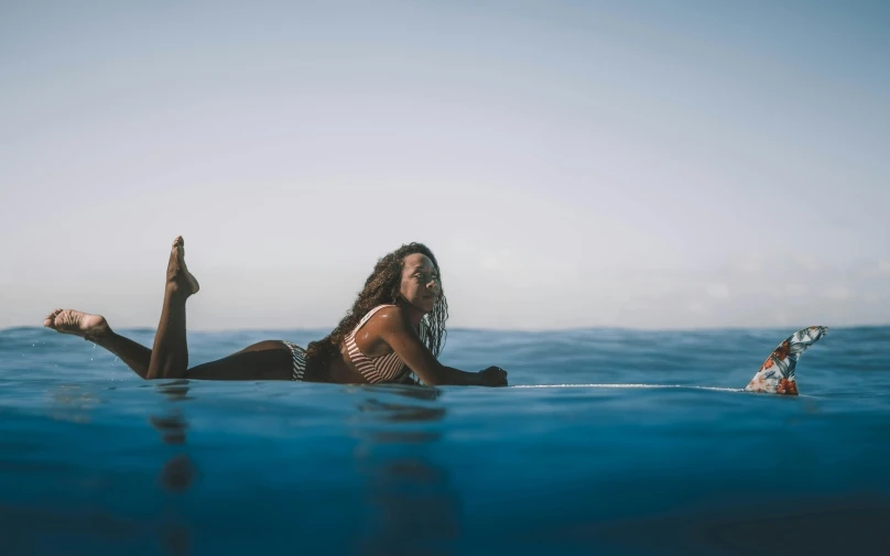 a woman is lying on the surfboard in the ocean