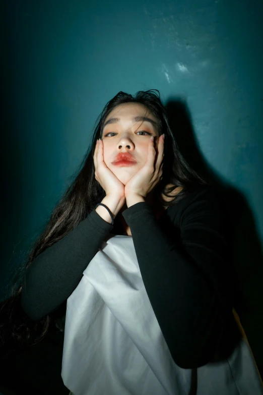 a woman sitting in front of a green wall