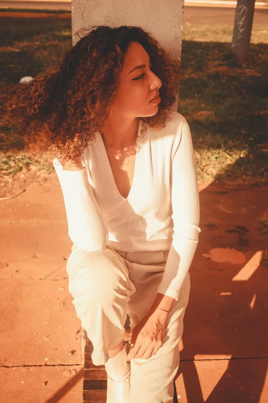 a girl wearing all white on a bench in the park