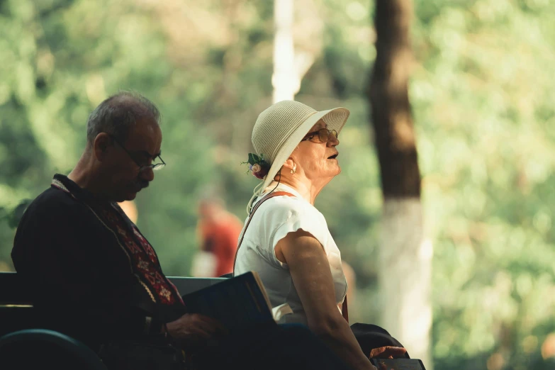 two people sit next to each other outdoors in the shade