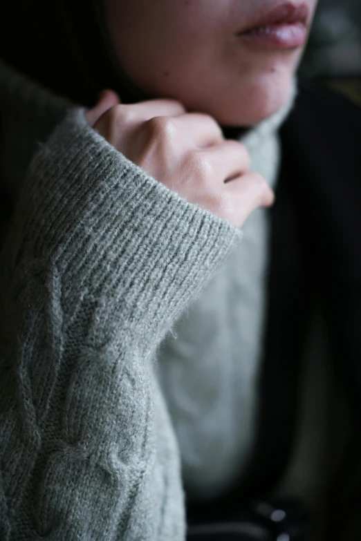 a woman with a black beanie holding onto the sleeves of her sweater