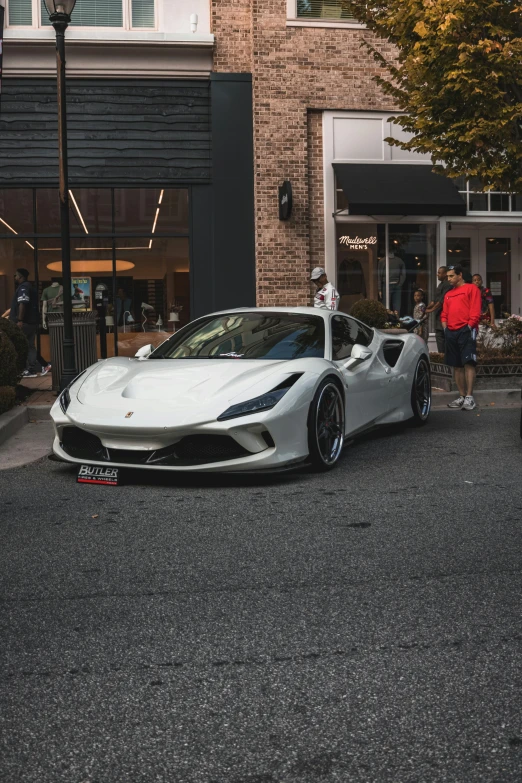 a man standing near a white sports car in the middle of a street