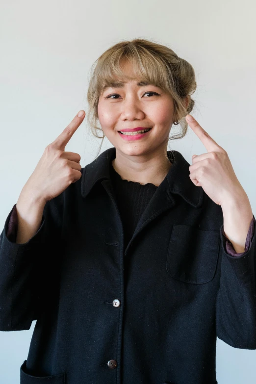 young woman smiling and raising her fingers up in front of her face