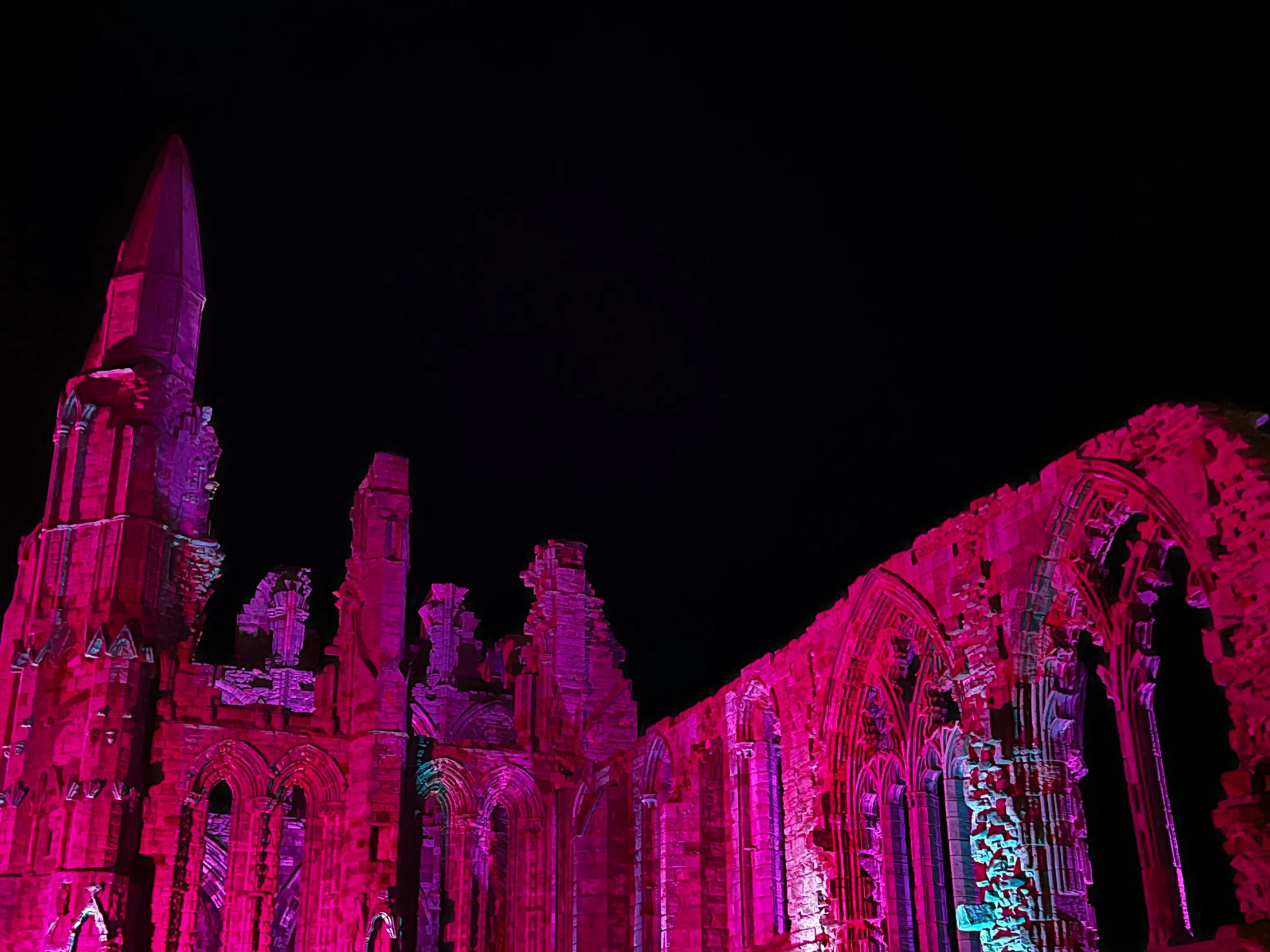 pink and purple lights illuminate the architectural structures of an old building