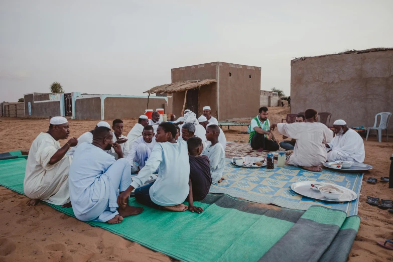 people sitting in a desert setting having a meal