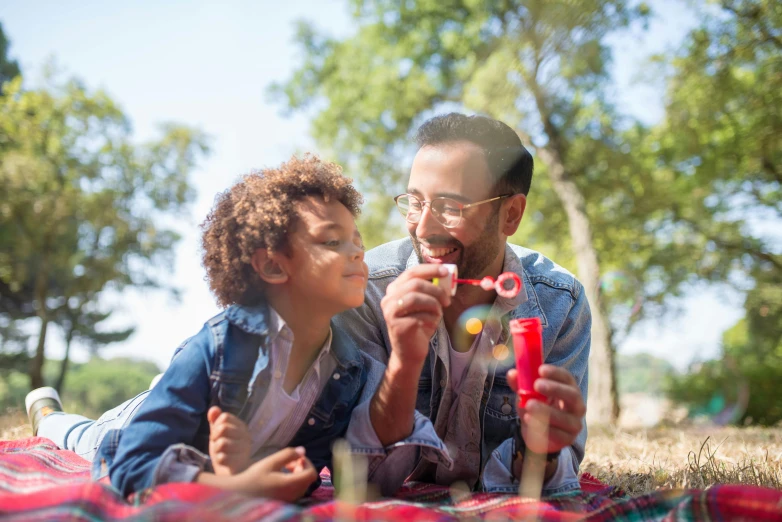 a man playing with his son under the shade of trees