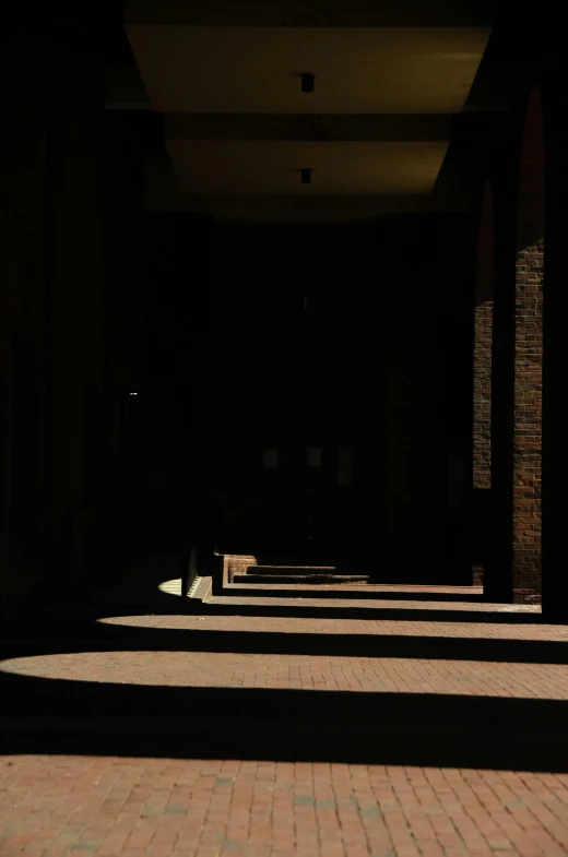 a hallway with brick and brick pillars is shown in the shadow