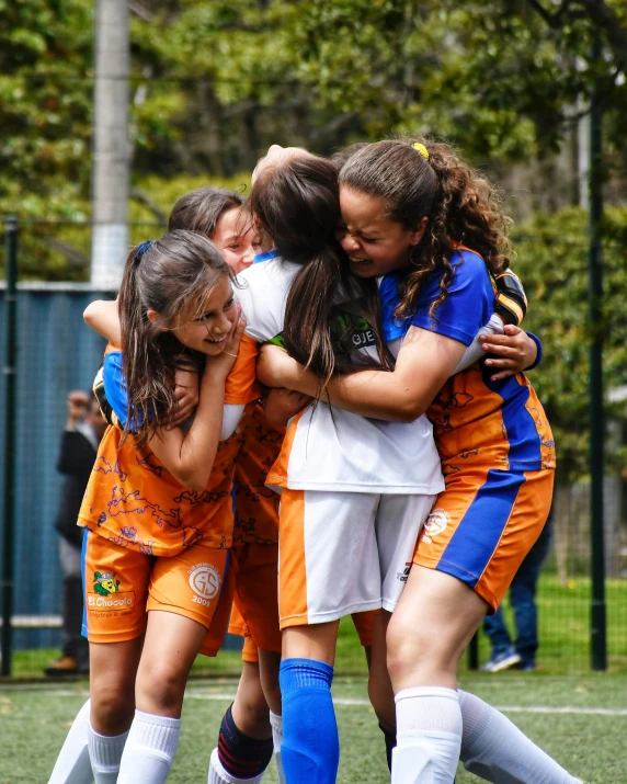 girls soccer team hugging and giving each other a hug