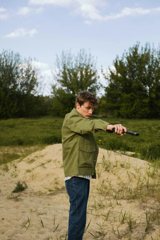 a boy swinging a bat in a field with tall grass