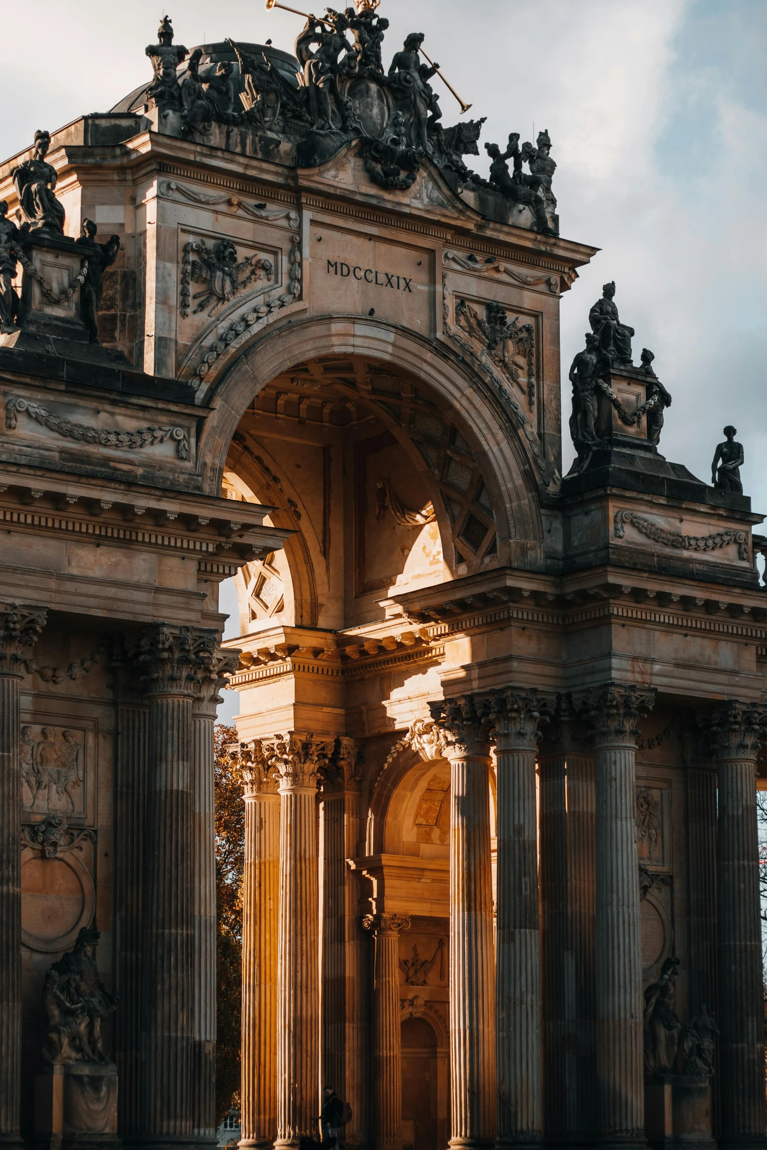 an arch with statues in it sits at the end of a street