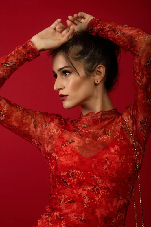 a woman wearing a red dress poses with her hands on her hair