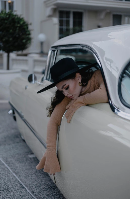 the woman is leaning on a classic car in the street