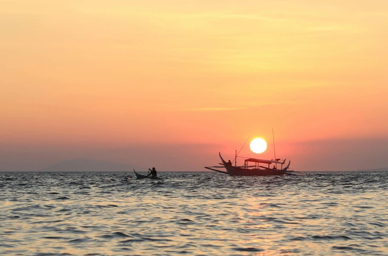 the sun is rising over the water and there is a boat in the water