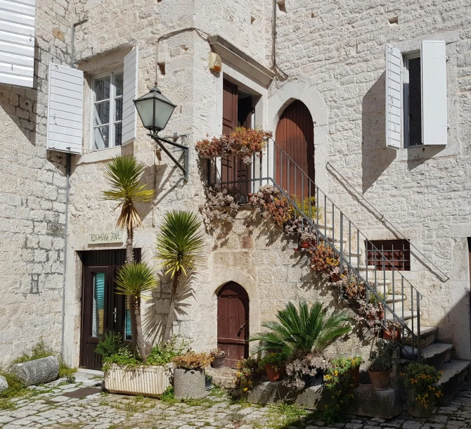 a white stone building with several plants and stairs