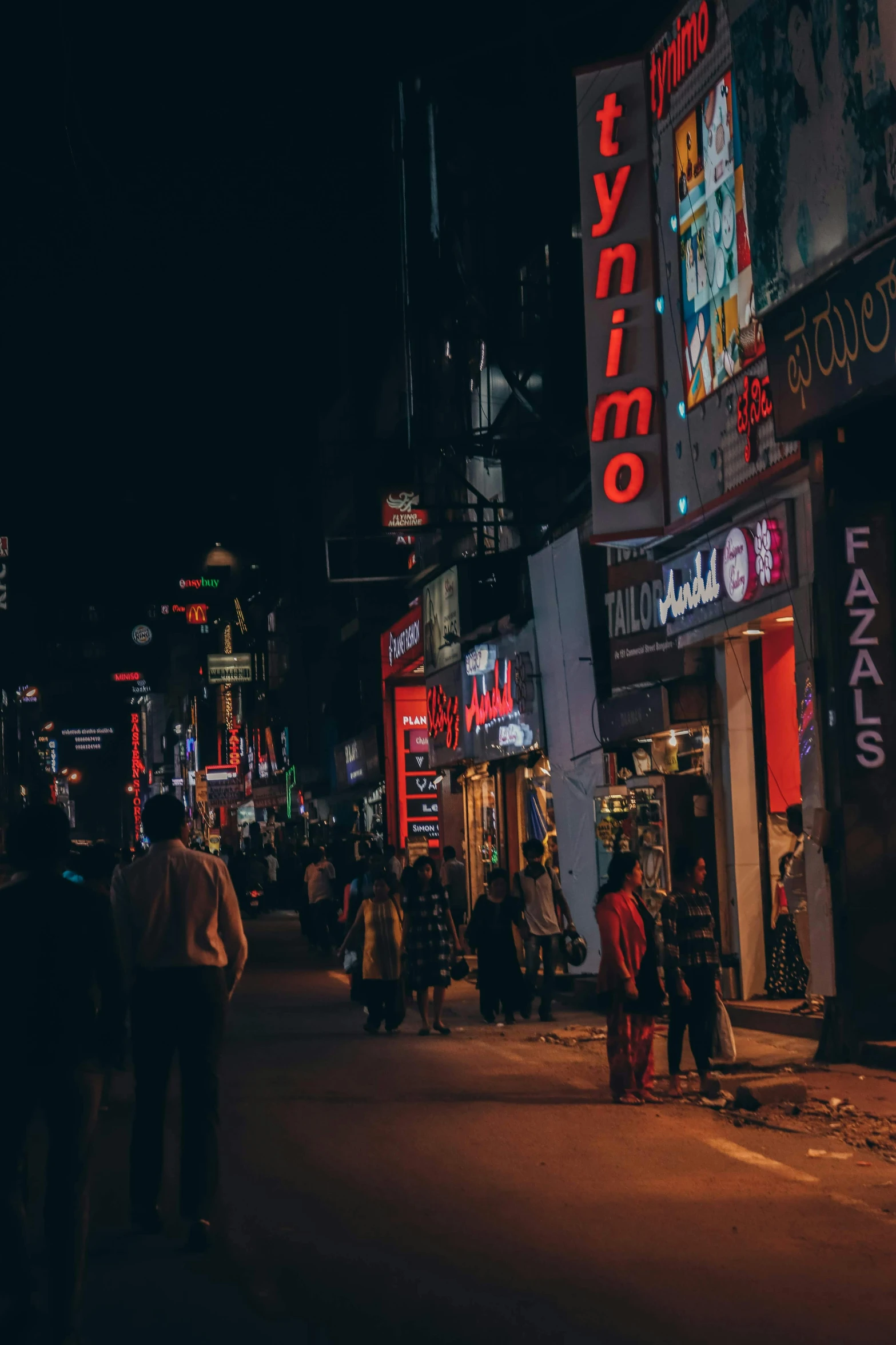 several people walking down the street on a nighttime in a city