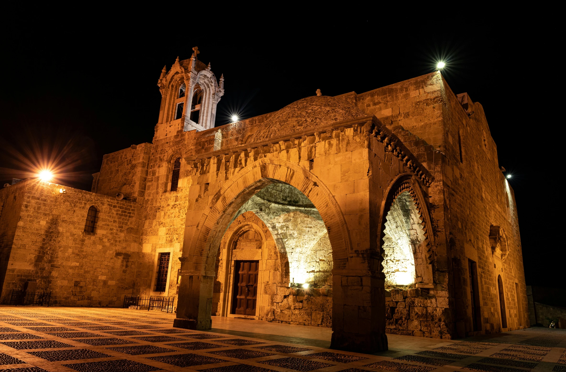 a large building has a stone floor and archways at night