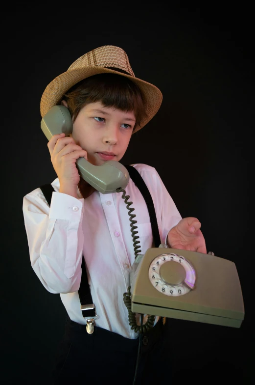 a little boy wearing a hat holding up a phone