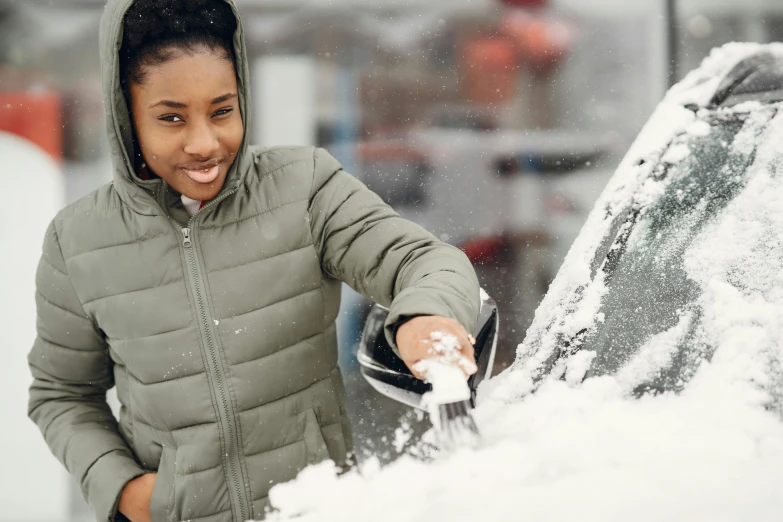 a woman is removing snow from her car