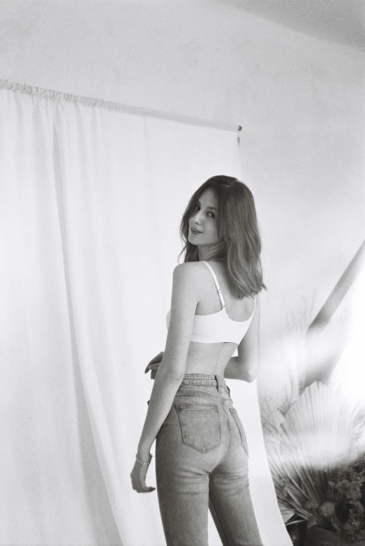 a woman standing next to a white curtain in the dark