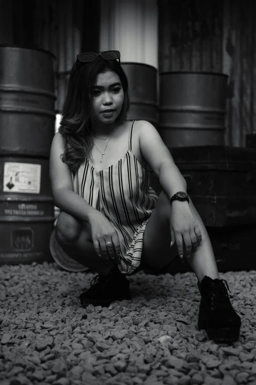 a woman crouching next to some barrels