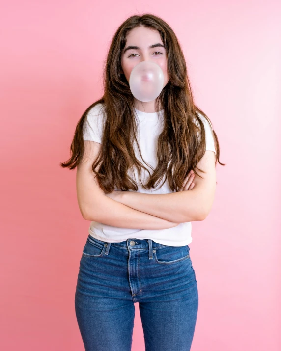 a girl in jeans, white t - shirt and a bubble in her mouth