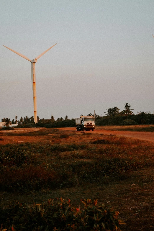 the truck is driving past the windmills that look to be very tall