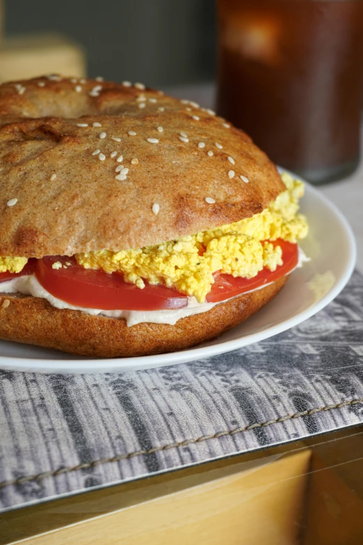 a breakfast sandwich made with an egg and tomato on a white plate
