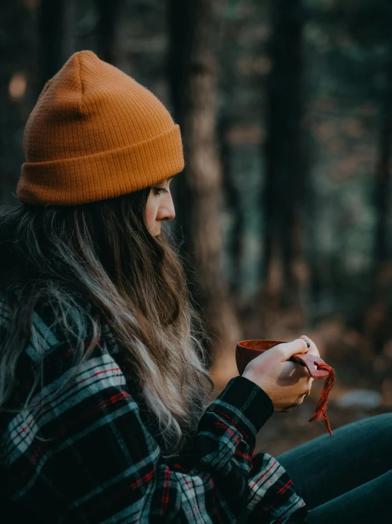 woman in plaid jacket and hat holding up a piece of food