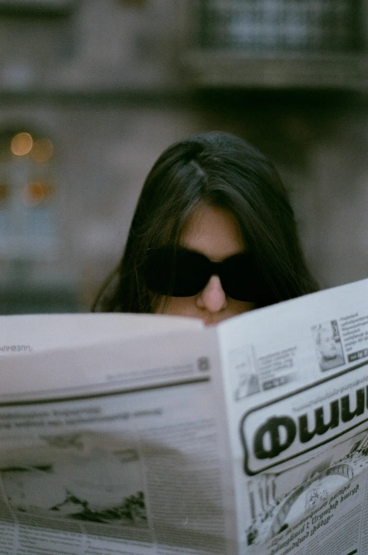 a woman looking at the newspaper wearing sunglasses