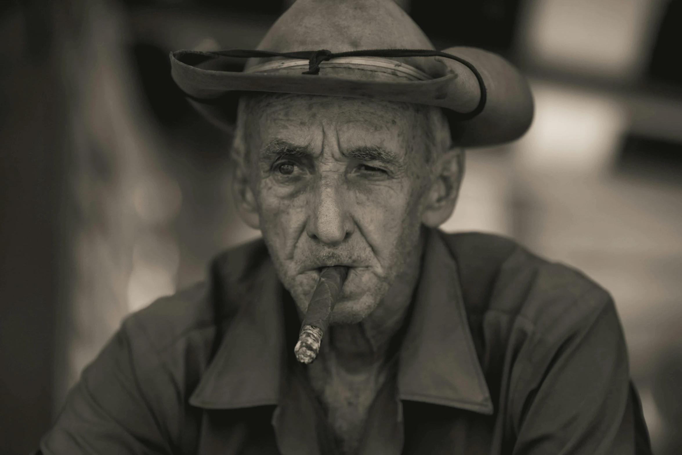 an old man smoking a cigar wearing a cowboy hat