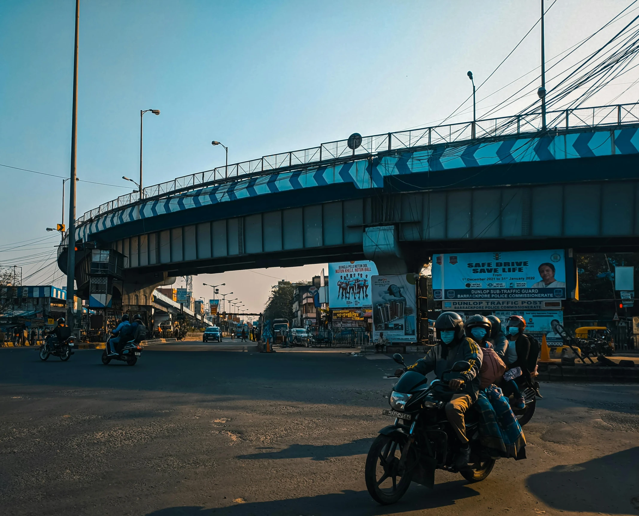 the motorcyclists are waiting at the traffic light to cross the bridge