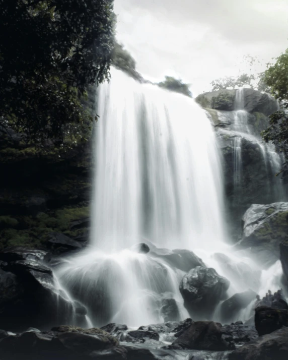 waterfall falling down into the forest surrounded by greenery