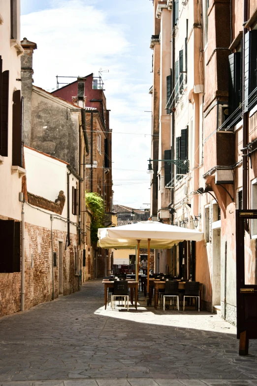 tables, chairs and an umbrella outside in the middle of a street