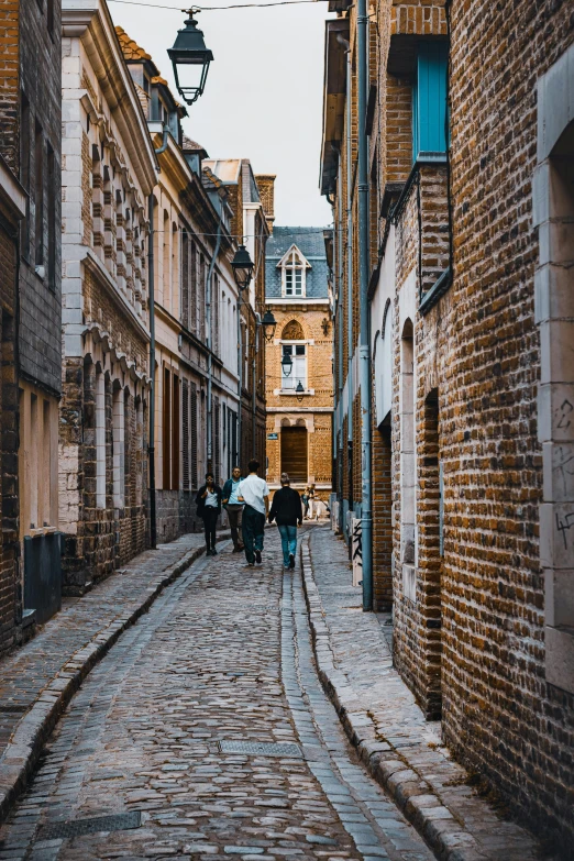 several people with umbrellas walking down a cobblestone street