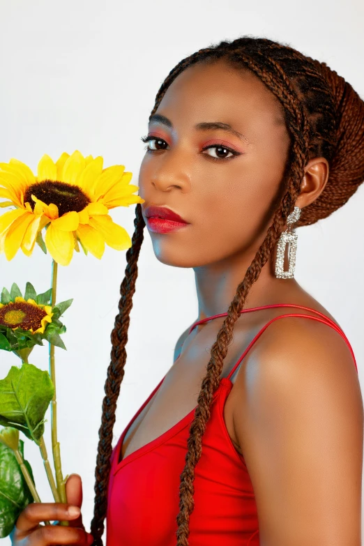 a woman holds a large yellow flower next to her face