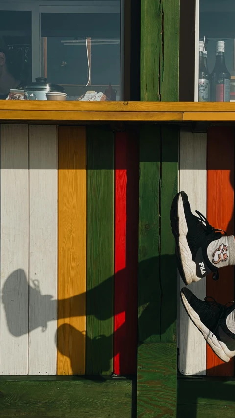 person standing on bench in front of rainbow colored wood