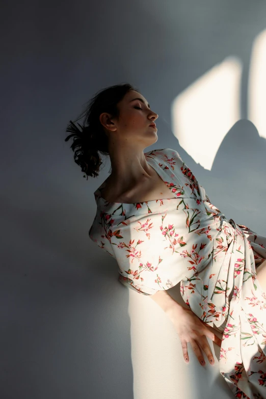 woman laying down on the ground next to a white wall