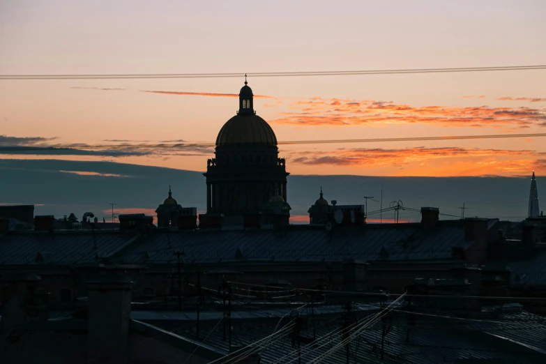 the sunsets behind the dome of a building in the city