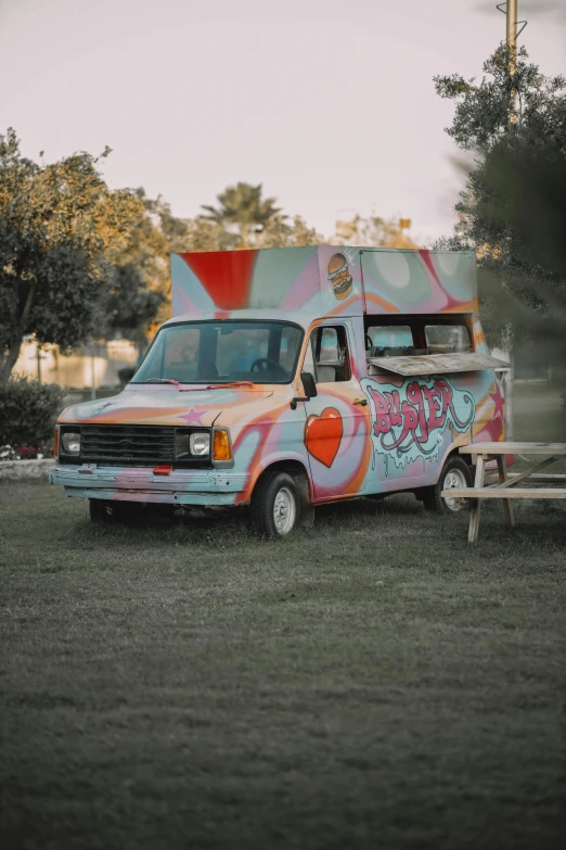 an ice cream truck with a graffiti theme sitting on grass