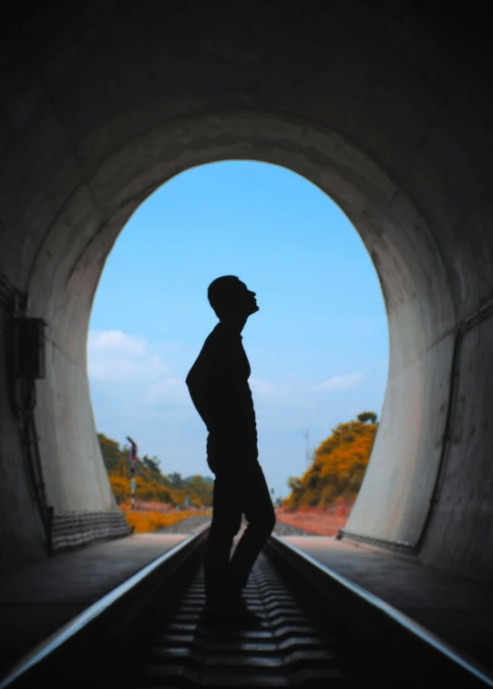 a man is standing on the tracks of the tunnel