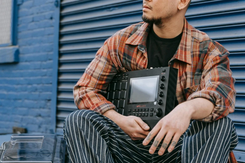 the man is holding a laptop sitting on a bench