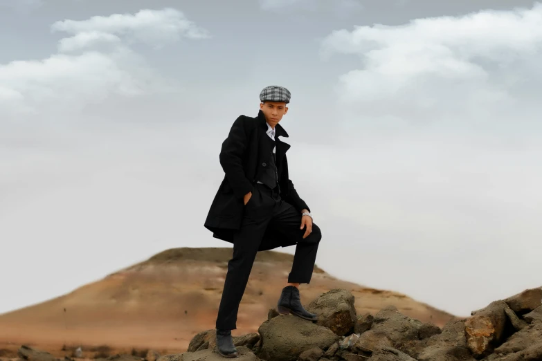 a man sitting on a rock wearing black and grey clothes