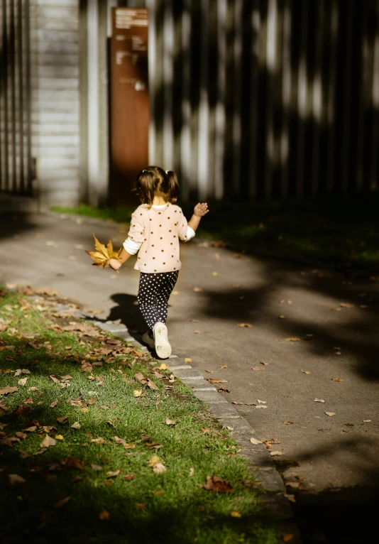 a little girl in a pink shirt running down the street