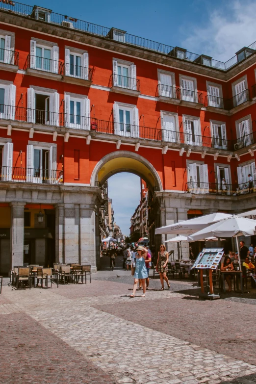 people walking past an old building with a tall archway