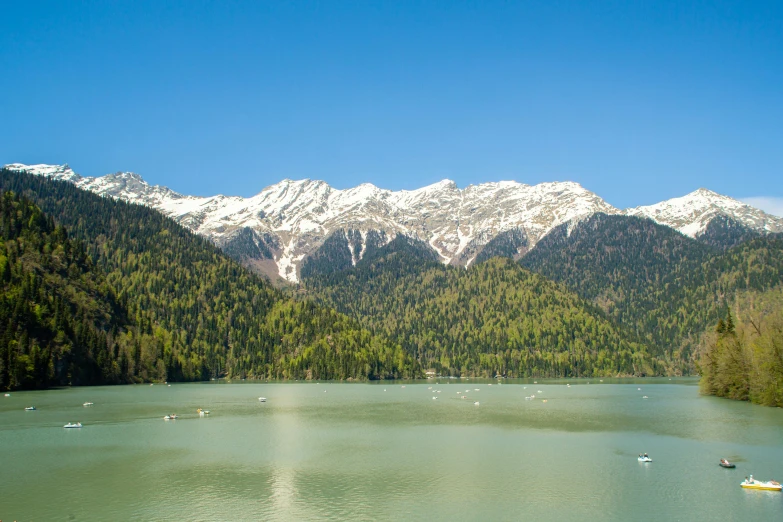 there are mountains in the distance as boats are on the water