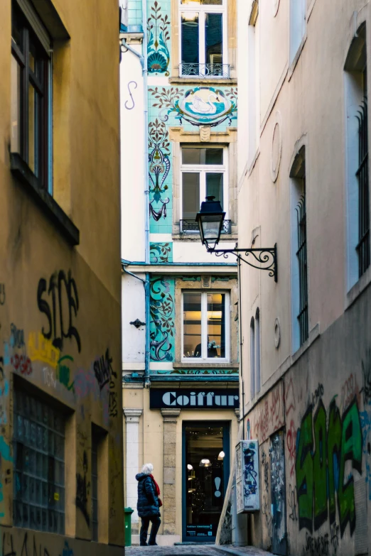 a woman standing in an alley next to a building