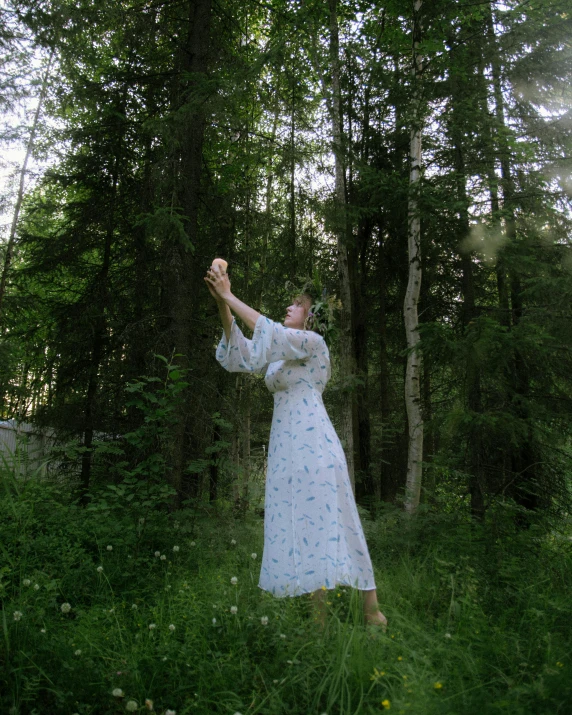 a woman in a long white dress in a forest