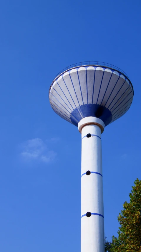 a large white tower with a blue top near some trees