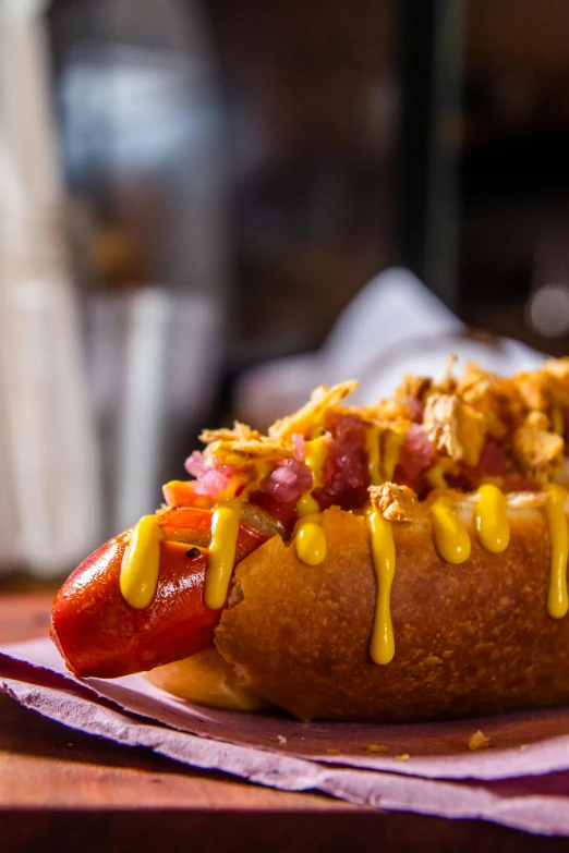 a  dog bun with toppings and mustard on a napkin